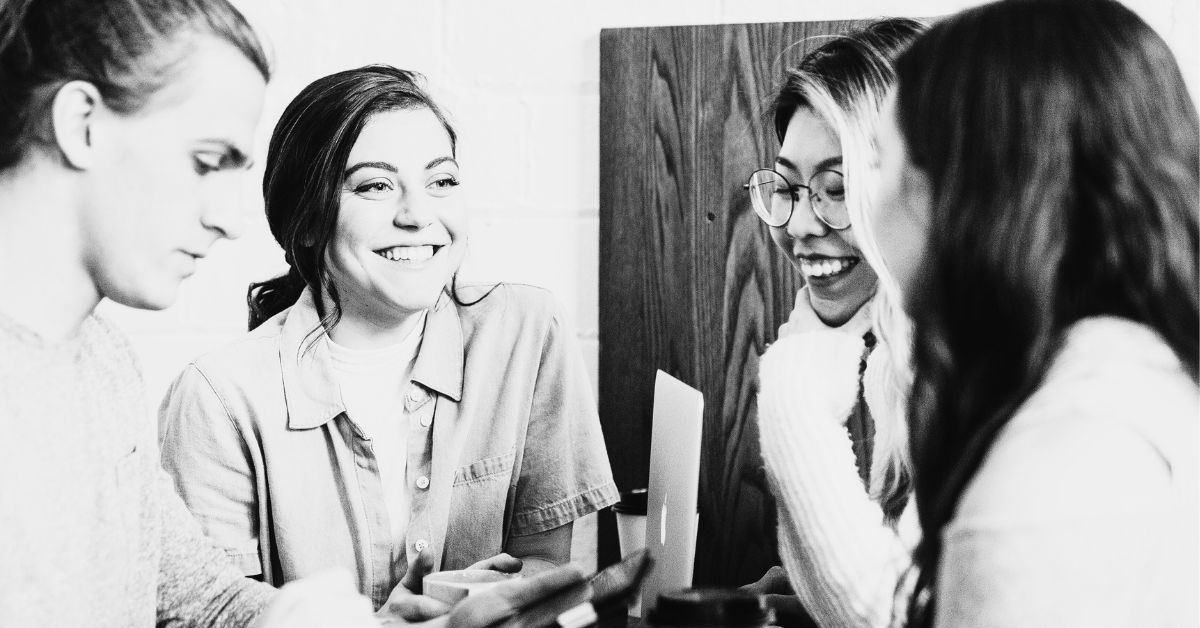 4 young colleagues chatting with laptop and coffee